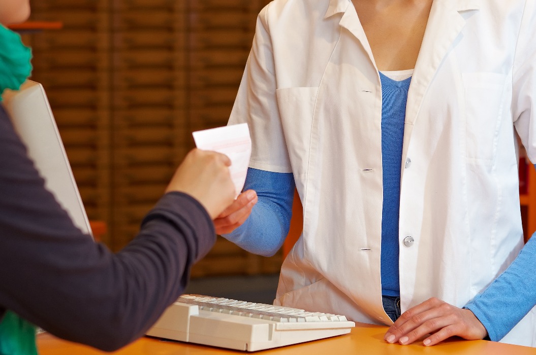 Kundin reicht Apothekerin ein Rezept